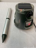 Photo showing ultrasonic animal repellent device and silver garden stake on white background