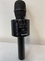 Front view of BONNOK black Bluetooth karaoke microphone showing microphone head and control panel including buttons for mode, volume, echo, music and power switch.