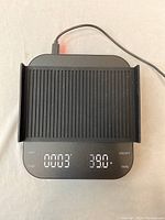 Top view of the digital coffee scale showing illuminated digital display with weight and time, USB connected.