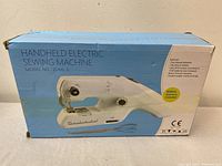 Box of Handheld Electric Sewing Machine model ZOM-6 with key features and image of the machine