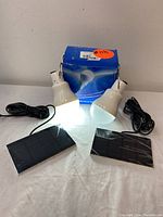 Two illuminated portable solar light bulbs with hanging hooks, cables, and two solar panels in original packaging box.