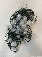 String lights coiled with multiple crackled clear globe bulbs attached to green wiring.