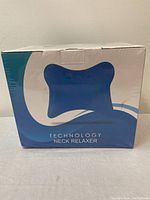 Front view of sealed boxed Technology Neck Relaxer showing blue and white packaging with product image and name.