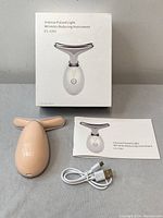 Photo showing the box of the Intense Pulsed Light Wrinkles Reducing Instrument ES-1081 with the instrument, charging cable, and manual laid out.