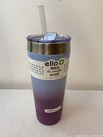 Side view of the tall insulated tumbler showing gradient purple to blue color and silicone grip band with branding.