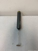 Top view of the gray handheld milk frother showing the whisk attachment and button control