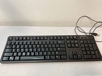 Black Insignia wired keyboard with USB cable on a light-colored surface showing the full QWERTY layout and numeric keypad.