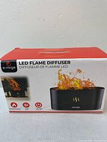 Box front showing e.mrge LED Flame Diffuser branding, image of diffuser with flame effect and control buttons.