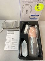 Top view of the box contents showing powered earwax remover in plastic mold, soft grey storage pouch, instructions.