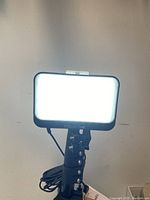 Close-up of the video light powered on, emitting bright white light from a rectangular panel.