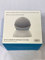 Front view of Mission Battery Base for Amazon Echo Dot 4th Gen box showing product image and key feature of up to 5 hours portable playtime.