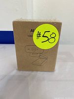 Front view of sealed cardboard box packaging showing the webcam illustration and '1080P' text, with a bright yellow circular sticker labeled #58.
