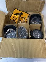 Four bullet-style dummy CCTV cameras neatly packed in a cardboard box; visible LEDs and mounting brackets included.