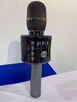 Front view of black Bluetooth speaker microphone showing mesh microphone head and control buttons on built-in speaker body.