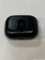 Top view of black rectangular charging case with a digital LED battery percentage display on the front.