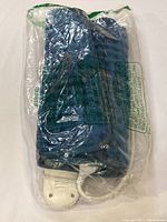 Blue wired heating pad inside clear plastic packaging, showing the attached white control switch and cord.