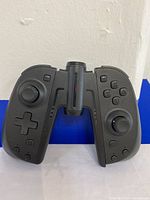 Front view of black ergonomic Nintendo Switch joy-pad with dual analog sticks, directional pad, and buttons.