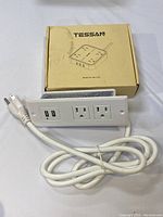 White TESSAN power bar with 2 standard power outlets and 2 USB charging ports, featuring a power cord and original branded box.