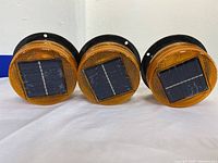 Front view of three solar LED light beacons showing amber lenses and solar panels.