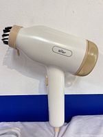 Side view of the Bear Brand clothes steamer showing white body, beige accents, and brush attachment at the steam outlet.