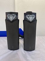 Front view of two Bluetooth computer speakers showing black mesh fronts and diamond light panels.