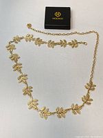 Full view of the gold leaf necklace laid out flat showing the entire length and leaf design.