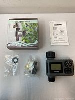 Photo of Insoma irrigation timer with box showing packaging and included accessories: two adapters/connectors and user manual.