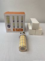 Photo of the packaging showing 6 LED light bulbs with a clear cylindrical shape and multiple yellow LED diodes on each bulb, with 3 bulbs boxed separately beside it.