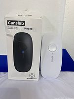 Photo showing white Canslab rechargeable automatic can opener next to its original box labeled 'Ultrablade Series Automatic can opener' indicating the device is white and rechargeable.