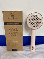 Photo of the Pink Cleen Bee hair brush next to its original cardboard box showing front and side.