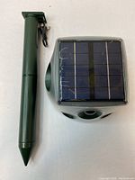 Top view of the solar panel on the animal repeller with the green plastic stake alongside it.
