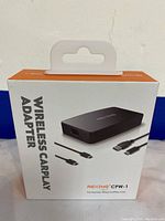 Box of REXING CPW-1 Wireless CarPlay Adapter showing product image and USB connectors illustration.