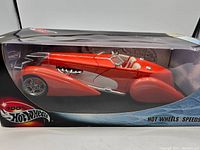 Side view of red Hot Wheels 1:18 scale Speedster in original box with clear display window and packaging showing brand