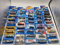 Full overview of 40 Hot Wheels cars still in original sealed packaging, arranged in rows showing variety of models and colors.