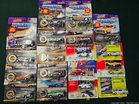 Overview of 18 Johnny Lightning 1:64 diecast cars in original sealed packaging arranged in three rows, showing cards with purple, yellow, green, and red backgrounds, and various car models visible.
