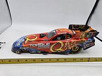 Profile view of the large Cruz Pedregon dragster model car showing detailed decals and orange/blue paint