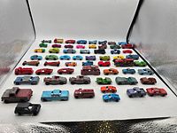 Wide view of 59 vintage Tootsie Toy mini cars including various colors and vehicle types, showing the overall quantity and condition.