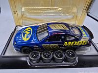 Blue Moog Chassis NASCAR diecast car at angle showing front and side details with four spare tires in front and original clear display box behind