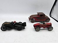 Three vintage steel diecast cars including two race cars and one coupe car.