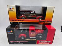 Two boxed diecast model trucks on stacked boxes: 1941 Chevy on top, 1947 International below, both packaging showing Parts Plus branding and Liberty Classics logo.