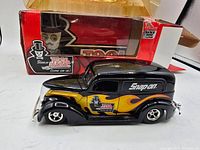 Side view of black Snap On diecast truck with yellow and orange flames displayed next to original Tool Magic branded box.