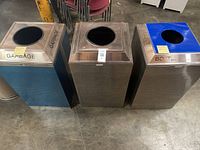 Set of three commercial trash bins side by side showing colors and labels.