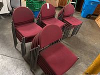 Stacked burgundy conference room chairs showing metal frames and seat design