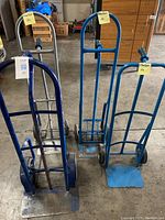 Four used hand truck dollies in various colors and conditions.