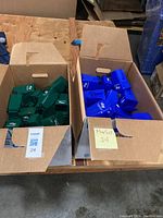 Two cardboard boxes filled with miniature green and blue trash bins featuring the UCSF logo.