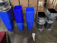 Stacked blue recycle bins and black lids wrapped in plastic, showing lot quantity and bin shape.