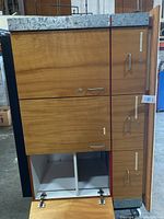 Front view showing the closed and open compartments with metal handles and door locks on wood grain finish.