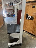 Full side view of the technical workstation showing black top surface, metal frame with caster wheels.