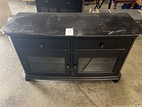 Full view of the brown TV console showing top, drawers, and glass doors with visible scratches and wear.