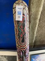 Close-up photo of wooden Aboriginal style painted boomerang with colorful dot and line patterns